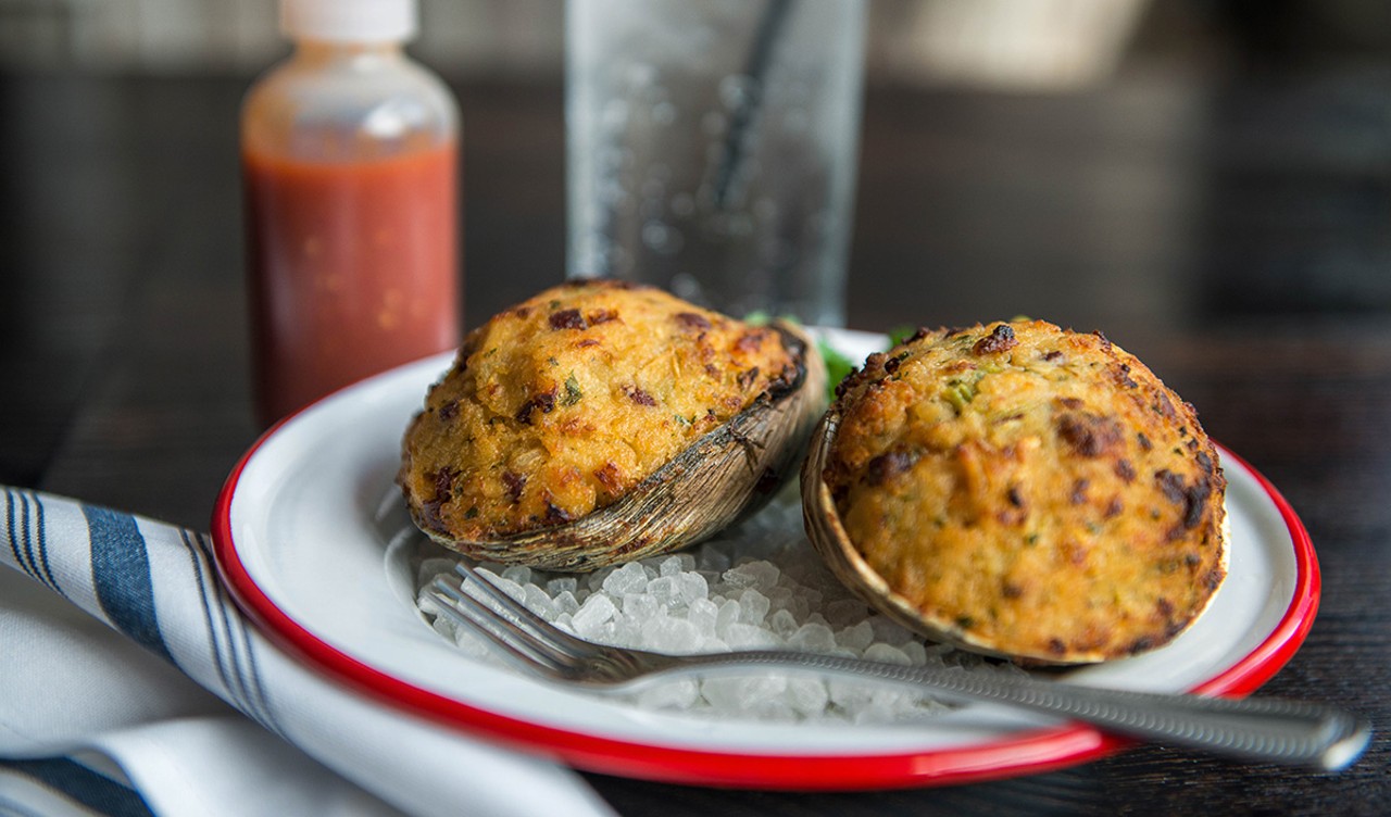 A plate with two baked clams on it.